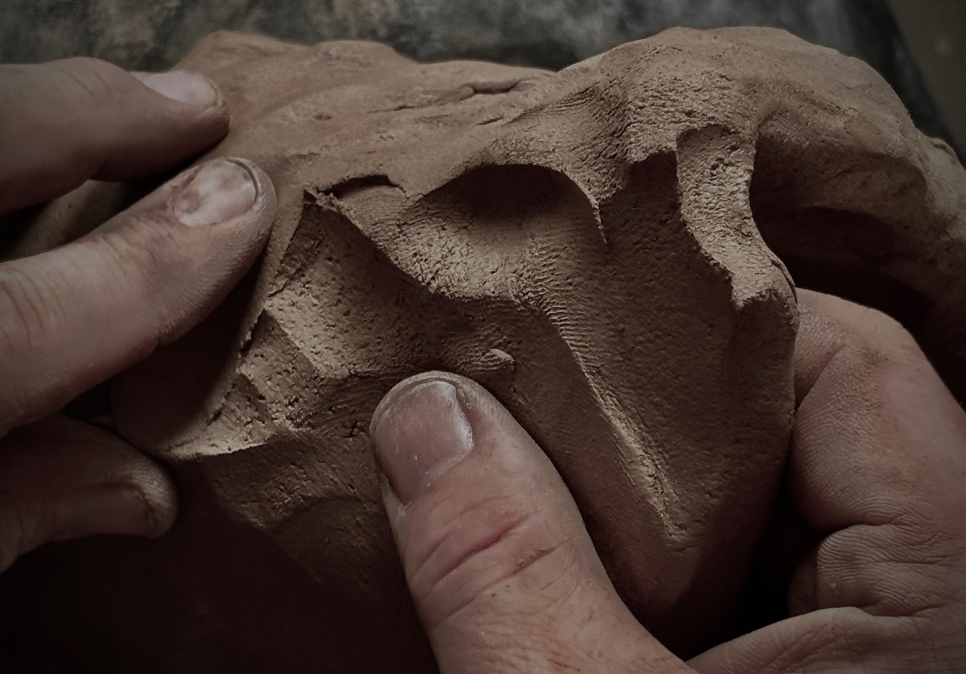 Hands working clay in the studio